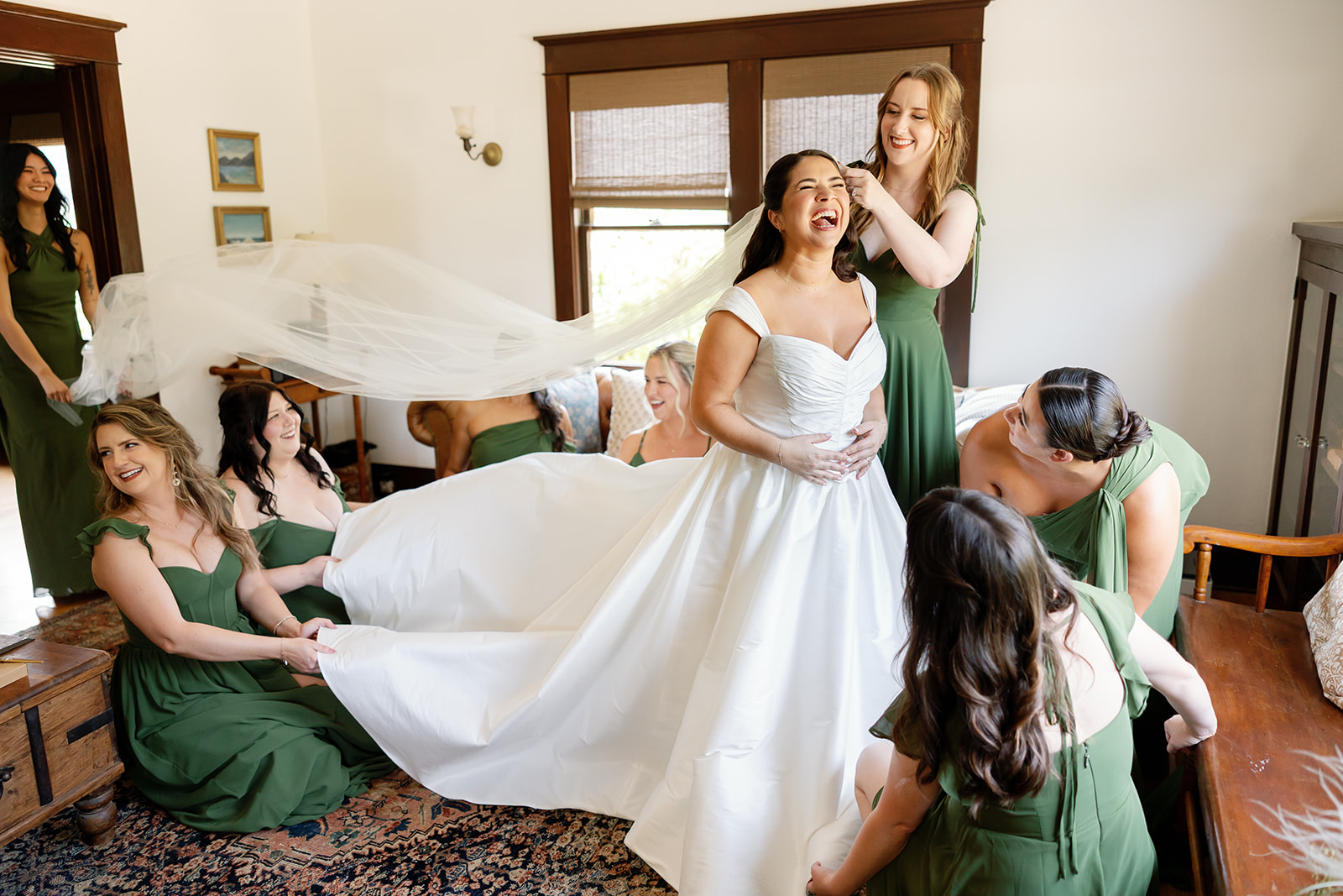 Candid photo of a bride laughing with her bridesmaids as she gets ready at The Swanner House in San Juan Capistrano, CA.