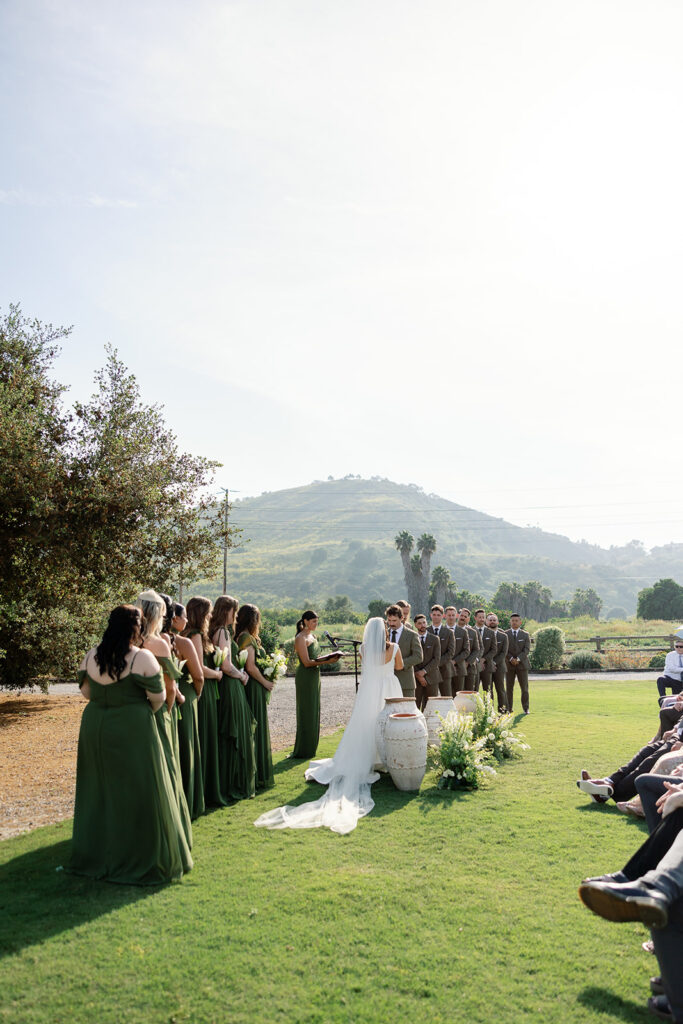 Wide view of an outdoor wedding ceremony on the lawn at The Swanner House in San Juan Capistrano, CA.