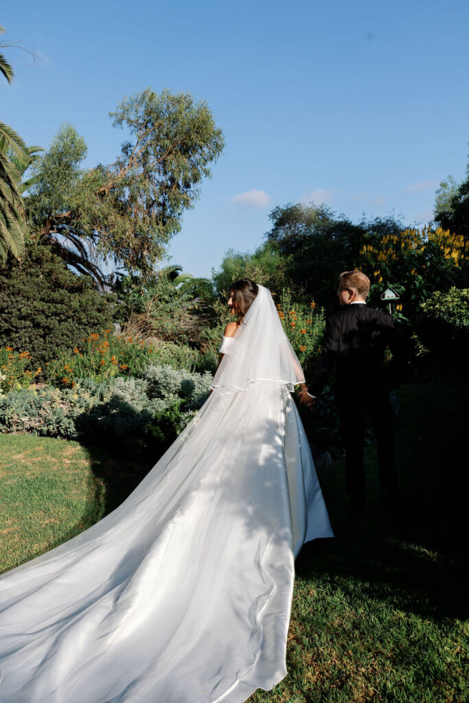 Bride and groom walking hand in hand through the gardens at McCormick Home Ranch during golden hour.