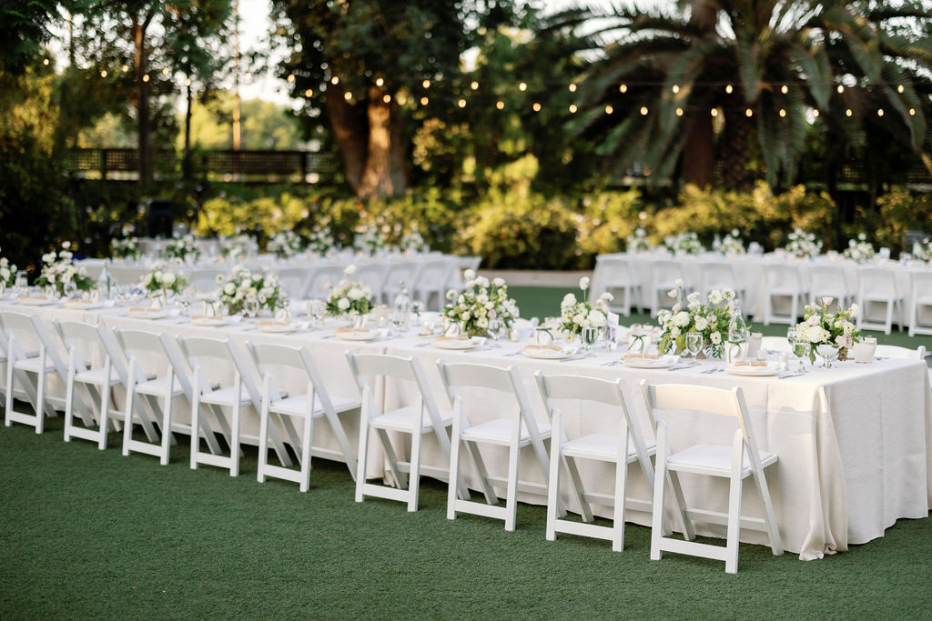 Long guest tables lined with classic white linens and florals during the circular lawn reception at McCormick Home Ranch.