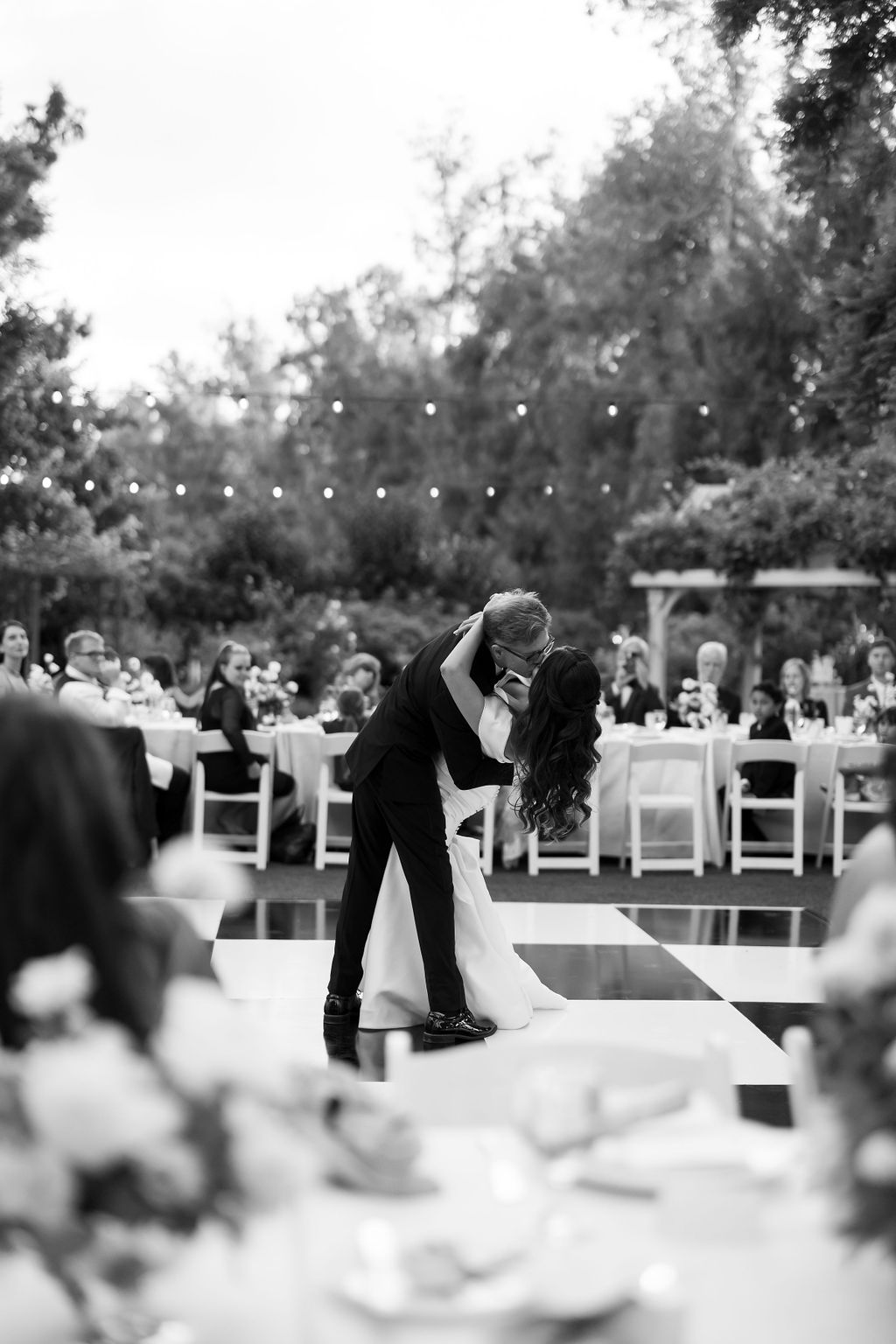 Couple sharing their first dance on the black-and-white checkered dance floor during their McCormick Home Ranch wedding reception.