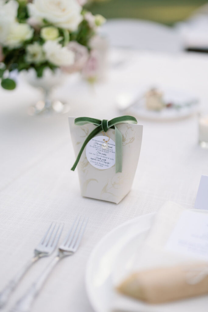 Italian bonbonniere favor with green ribbon at a guest’s place setting during a McCormick Home Ranch wedding reception.