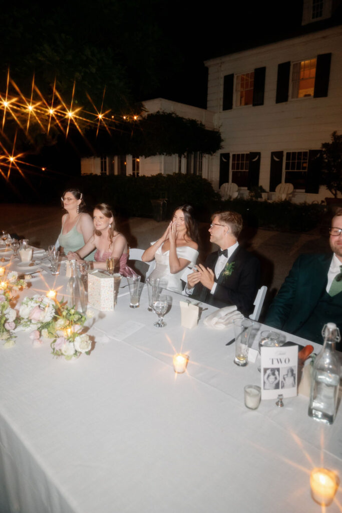 Wedding party seated at the head table under nighttime string lights during the McCormick Home Ranch reception.