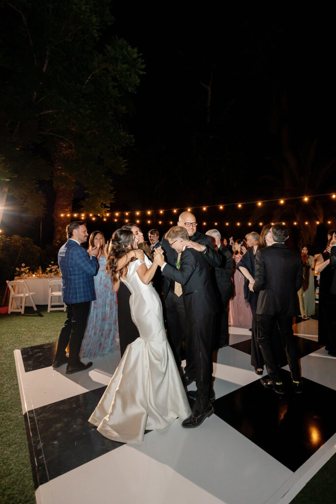 Guests dancing under string lights on the checkered dance floor during the McCormick Home Ranch wedding reception.