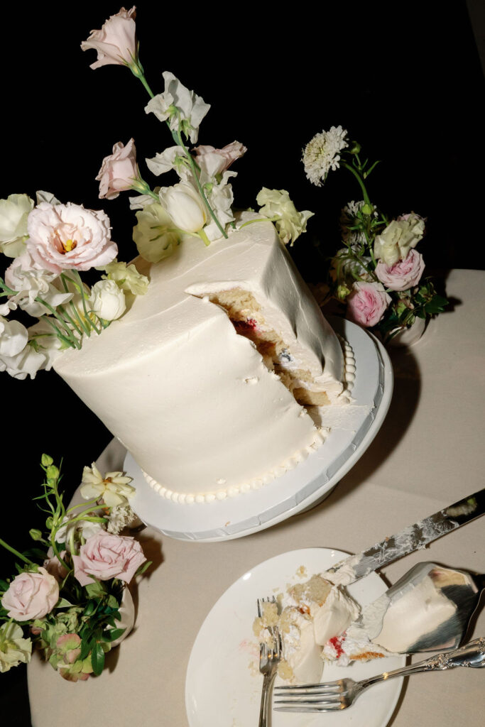 Wedding cake with floral accents after being cut during the McCormick Home Ranch wedding reception.