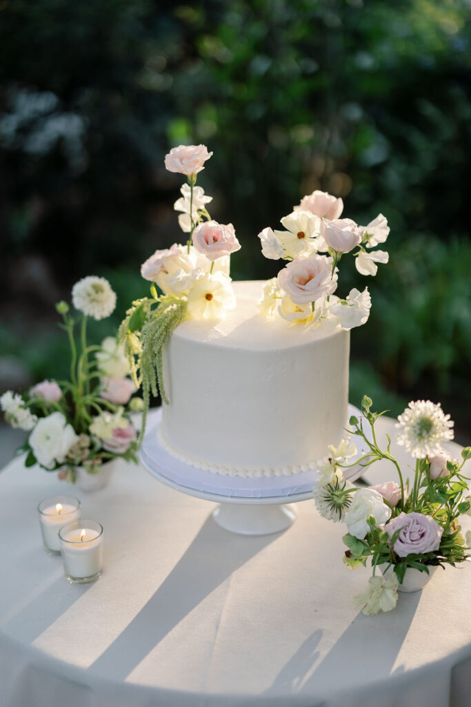 White wedding cake with soft pastel florals displayed during the McCormick Home Ranch wedding reception.