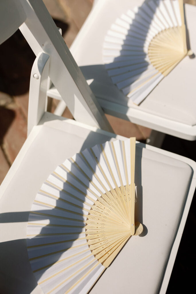 White fans for guests during an outdoor wedding ceremony in California