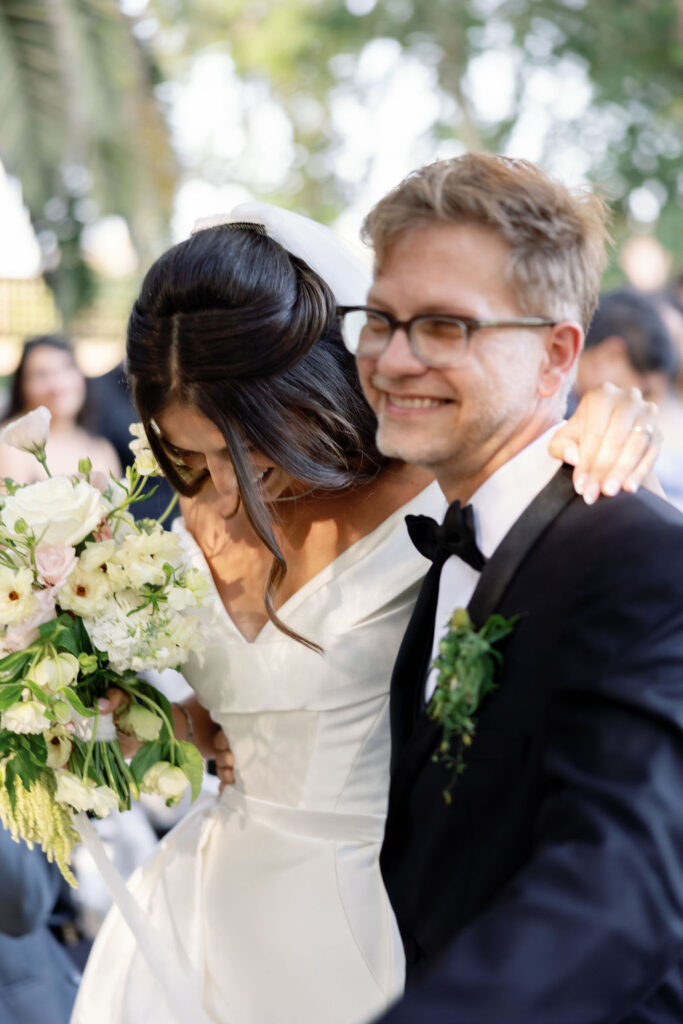 Bride and groom smiling and holding each other as they walk up the aisle after the ceremony.