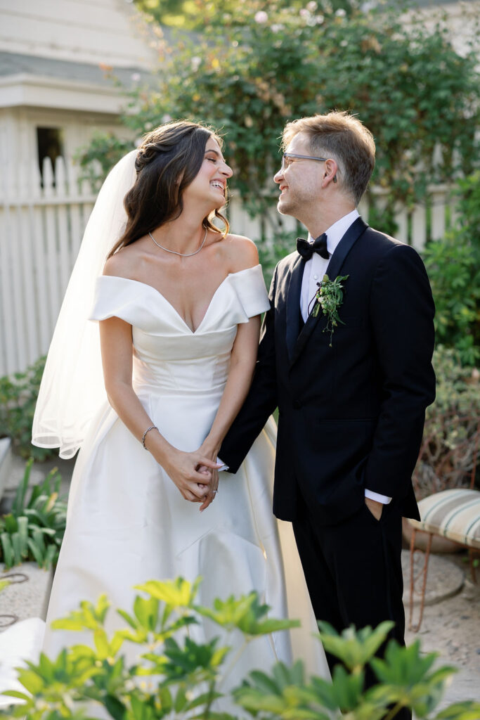 Bride and groom holding hands and smiling at each other in the garden after their ceremony