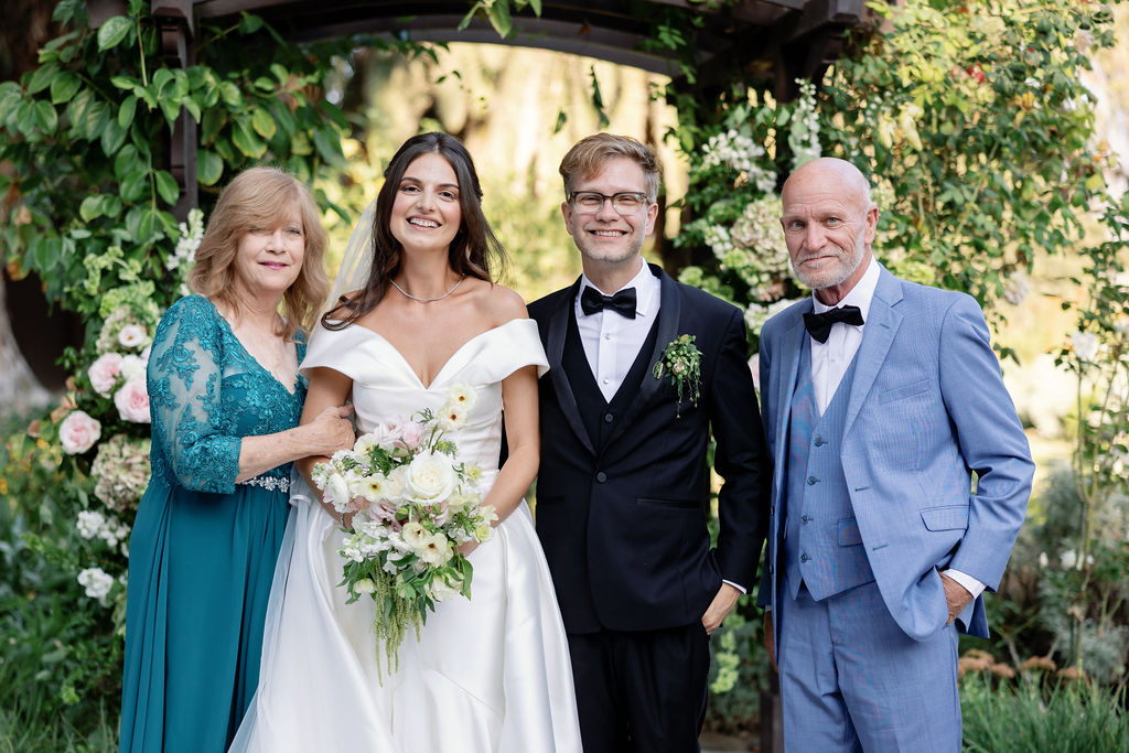 Bride and groom posing with the parents of the groom