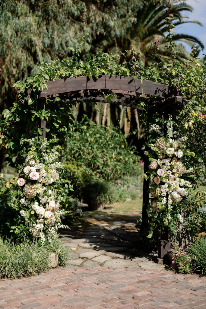 Wooden ceremony arbor covered in greenery and blush-and-ivory florals at McCormick Home Ranch.