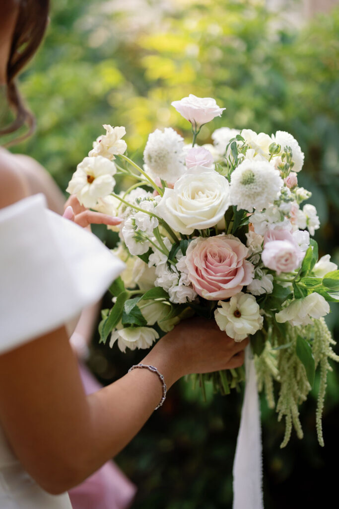 Close up photo of a bride holding a bouquet of white and blush florals by Brooke Bloom Co.