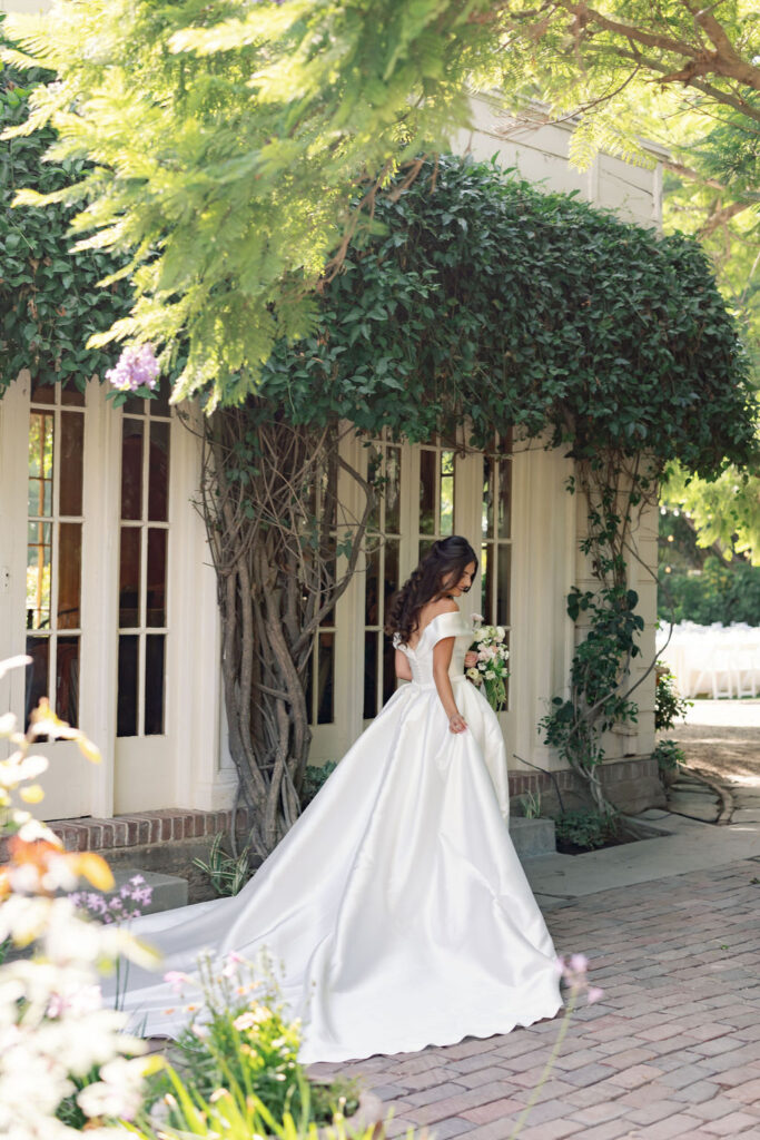 Bride walking with her bouquet in front of an ivy-covered building at McCormick Home Ranch.