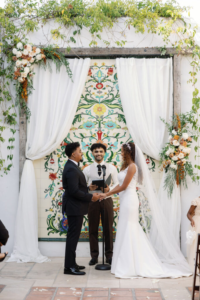 Bride and groom holding hands during their La Ventura San Clemente wedding ceremony in the Courtyard.