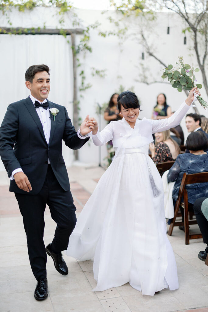 Bride and groom walking back down the aisle as husband and wife after their La Ventura San Clemente wedding ceremony in the courtyard.