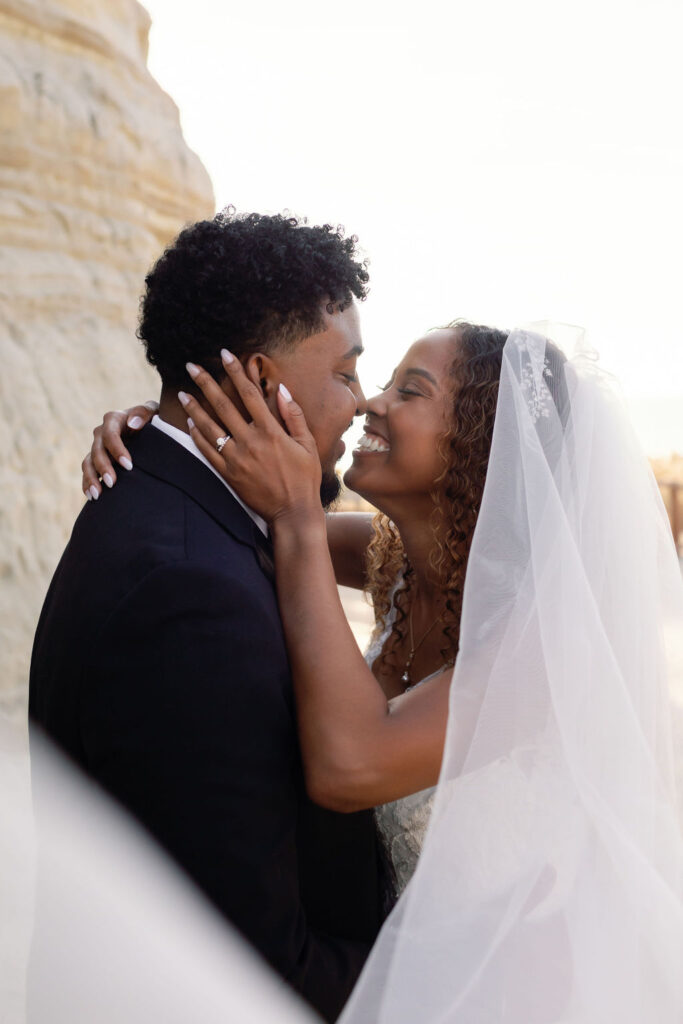 Close up shot of a bride and groom posing in front of San Clemente Sand Cliffs.