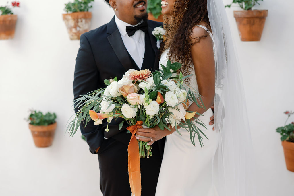 Wide shot of a bride and groom posing in in Spanish Potted Garden at La Ventura San Clemente.
