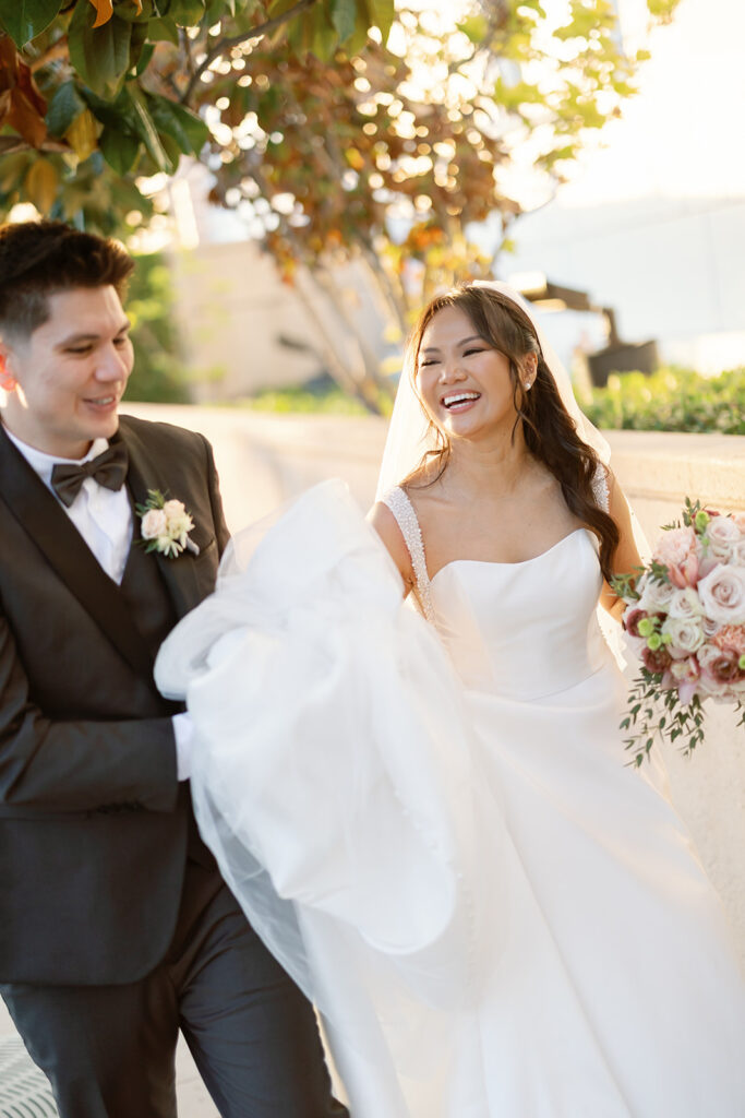 Candid portrait of the bride laughing while holding her dress during Nixon Library Yorba Linda wedding portraits.