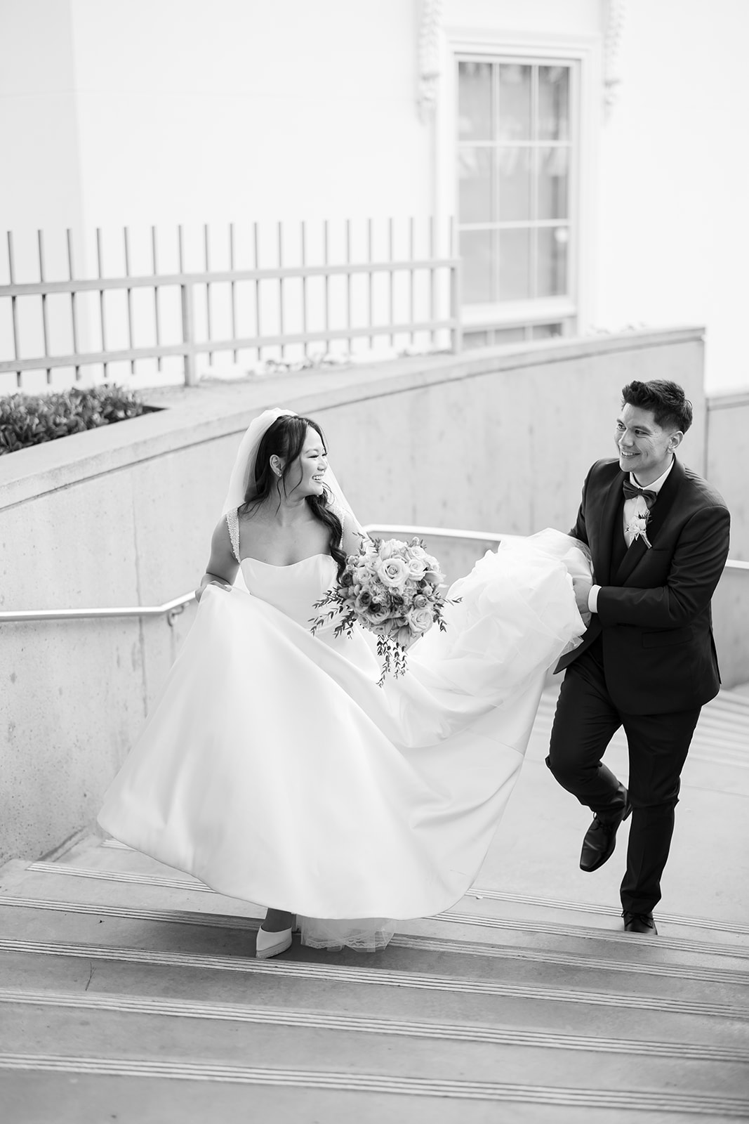 Black and white photo of a bride and groom walking up a staircase at Nixon Library in Yorba Linda.