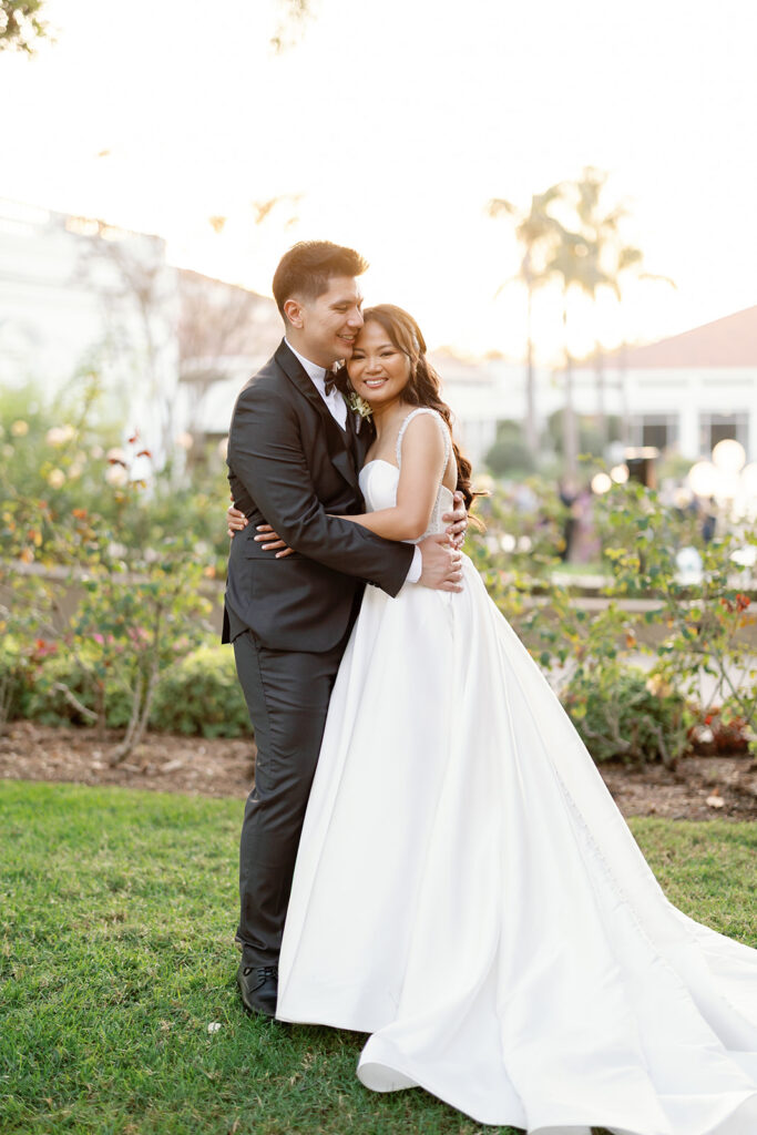 Bride and groom embracing in the gardens during sunset portraits at Nixon Library Yorba Linda wedding.