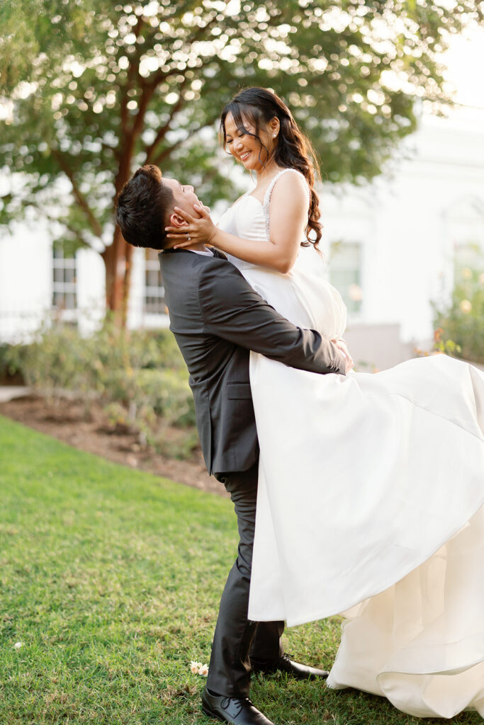 Groom lifting up his bride in the gardens at Nixon Library.