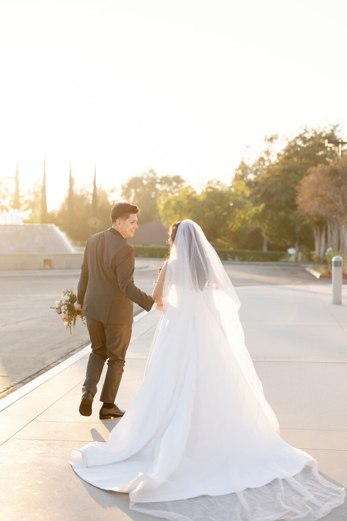Bride and groom walking hand in hand at sunset on the Nixon Library grounds after their ceremony.