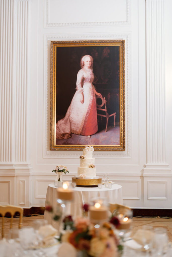 Wedding cake displayed beneath a historic portrait inside the East Room at a Nixon Library Yorba Linda wedding reception.