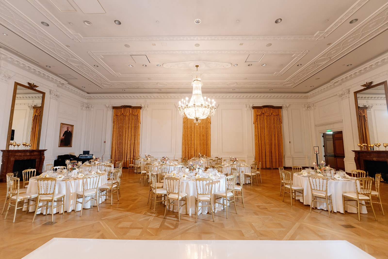 Wide view of the White House–style East Room reception at a Nixon Library Yorba Linda wedding, featuring chandeliers, gold chairs, and round tables set with white linens.