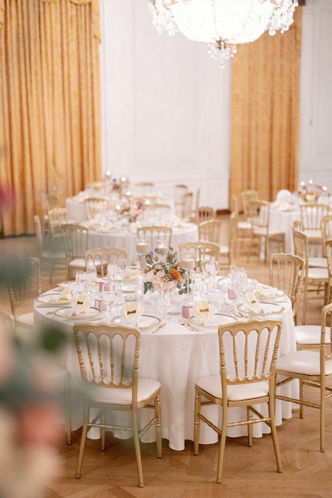 Candlelit reception tables set beneath chandeliers in the East Room at the Nixon Library in Yorba Linda.