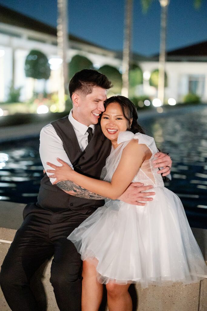 Bride and groom sit together by the reflecting pool during their Nixon Library Yorba Linda wedding night portraits.