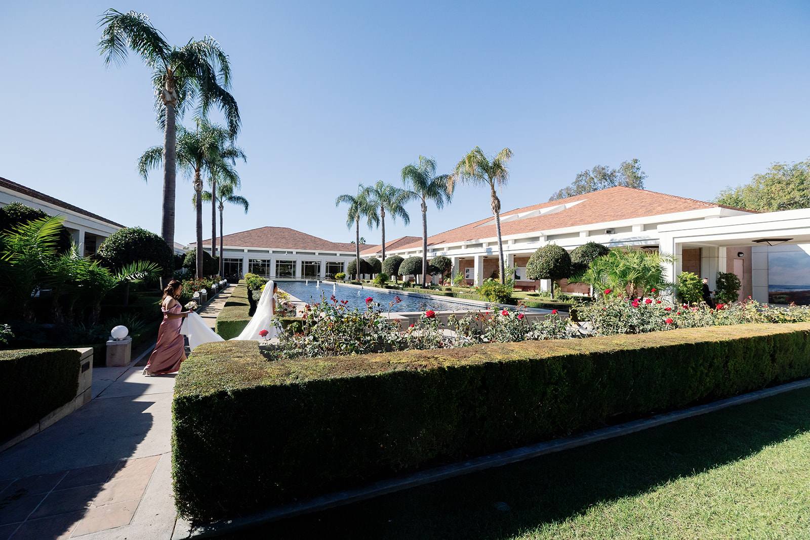 Bride walking through the Rose Garden at Nixon Library for a first look with the groom.