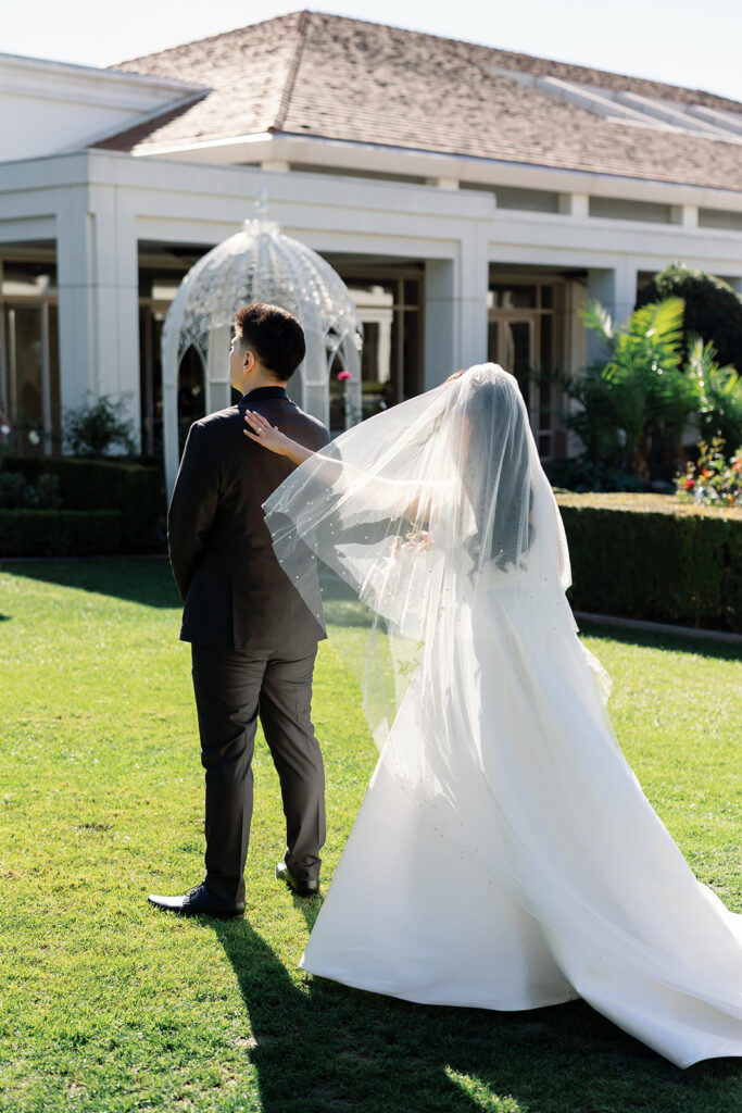 Bride approaching groom from behind for their first look in the Rose Garden at Nixon Library Yorba Linda wedding.