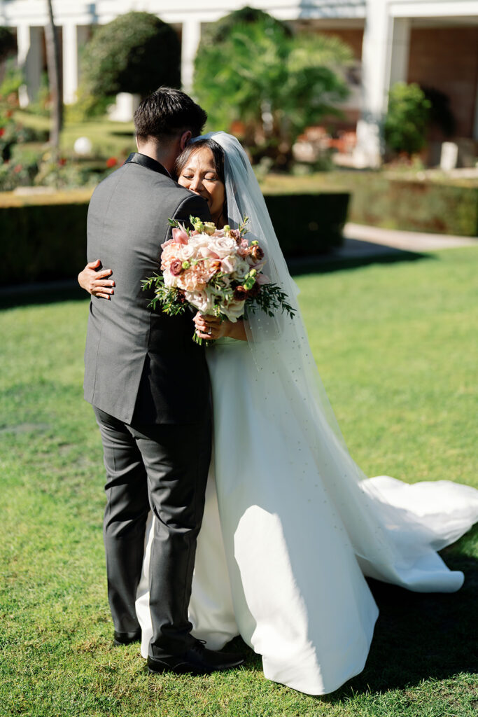 Bride and groom hugging during their first look in the Rose Garden at Nixon Library.