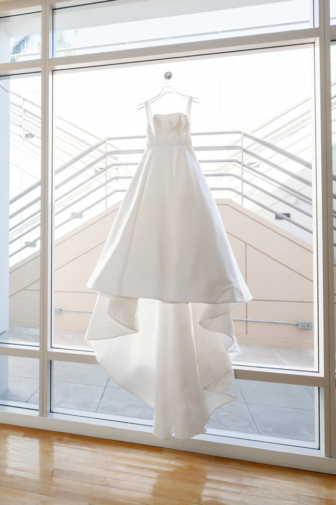Brides wedding dress hanging on the window.