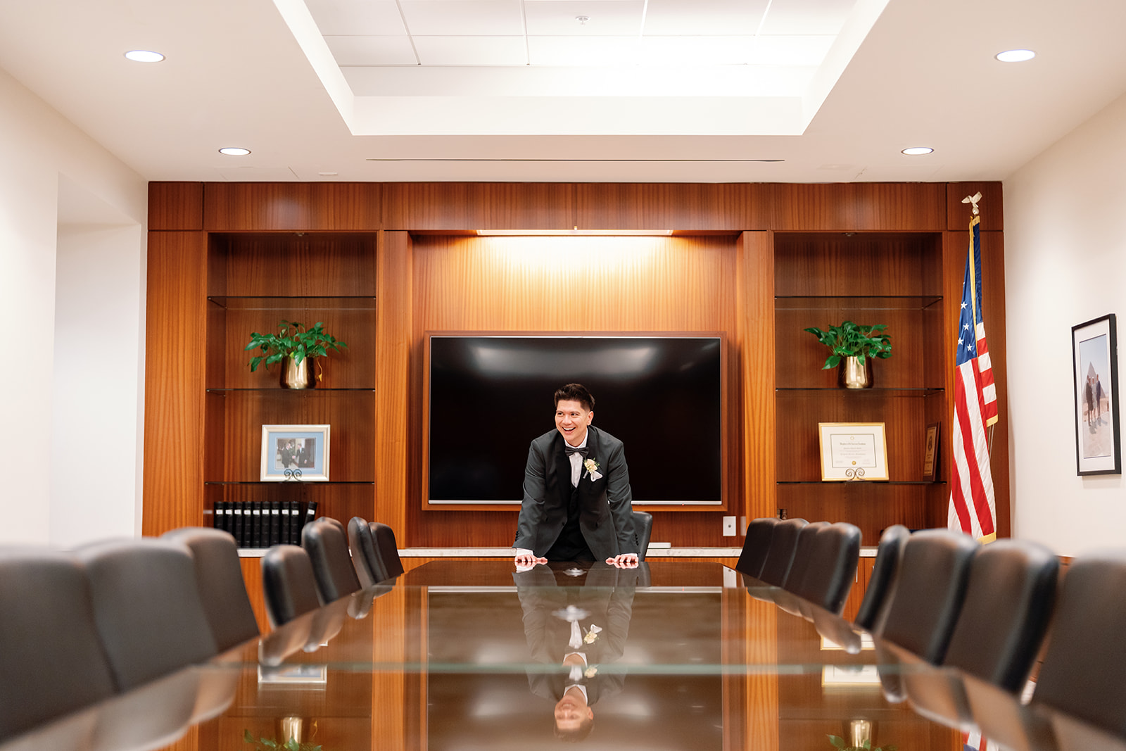 Groom leaning over a conference table inside the Nixon Library during wedding day portraits.