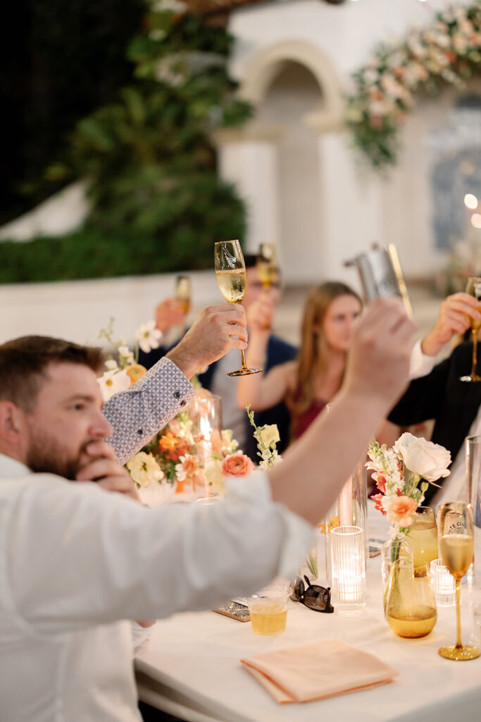 Guests raising champagne glasses during toasts at a Rancho Las Lomas wedding reception.