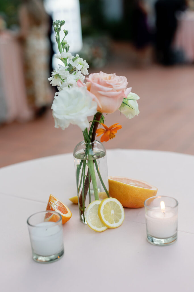 Citrus-inspired wedding table centerpiece with fresh florals, sliced lemons, and candles at a Rancho Las Lomas wedding reception.