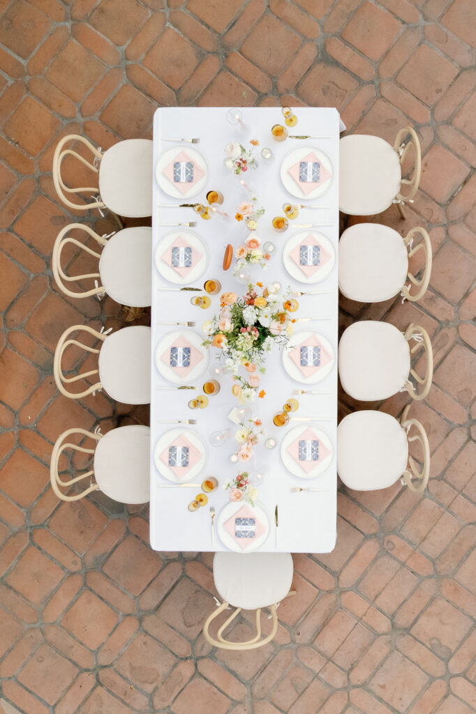 Overhead view of a long reception table styled with peach linens, citrus accents, and floral centerpieces at Rancho Las Lomas.