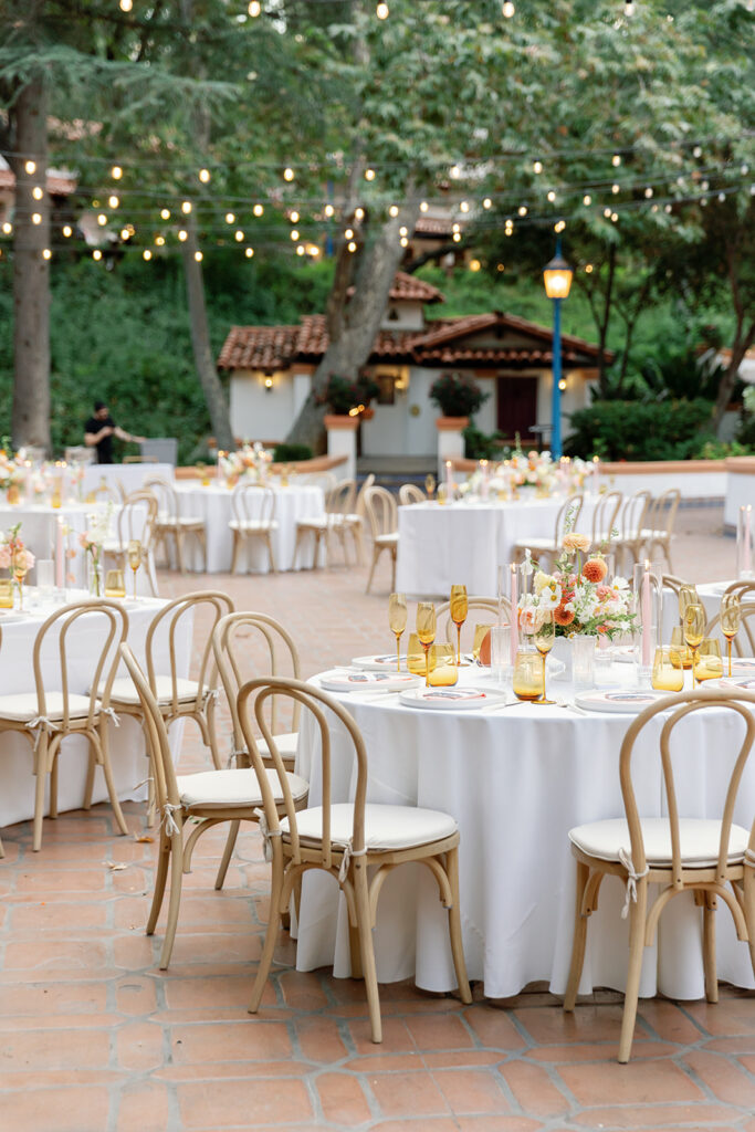 Outdoor reception tables set beneath string lights at Rancho Las Lomas wedding venue, featuring warm candlelight and garden surroundings.