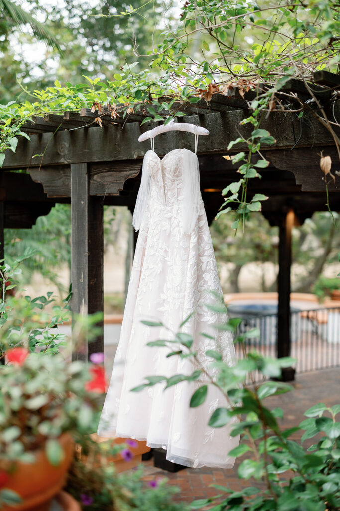 Wedding dress hanging under greenery at Rancho Las Lomas before the ceremony.