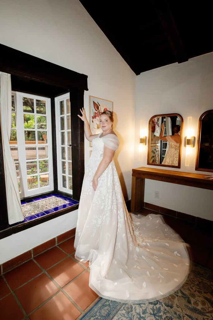 Bride standing in her wedding dress near a window inside Casa Abuela at Rancho Las Lomas.