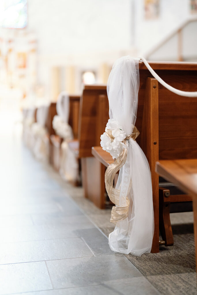 Church pews decorated for a St. Martin de Porres Church wedding ceremony in Yorba Linda.