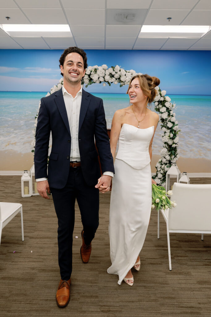 Bride and groom walking down aisle celebrating after Laguna Hills Civic Center elopement ceremony.