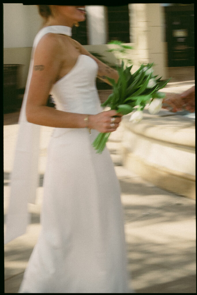 35mm film portrait of a motion blue photo of a bride walking with her bouquet in hand.