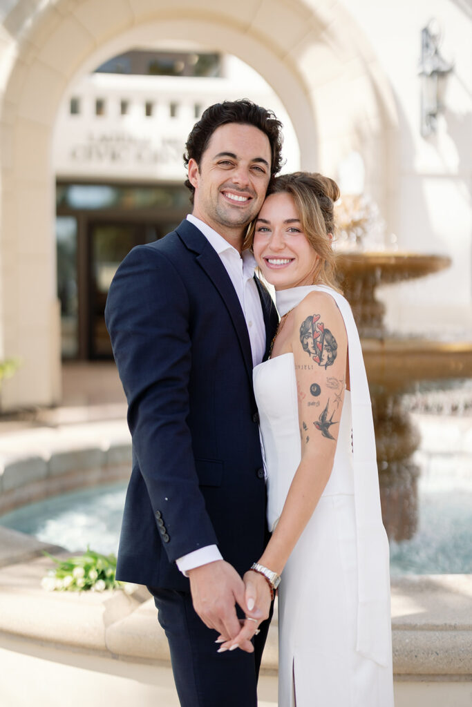 Bride and groom holding hands in front of Laguna Hills Civic Center during elopement portraits.