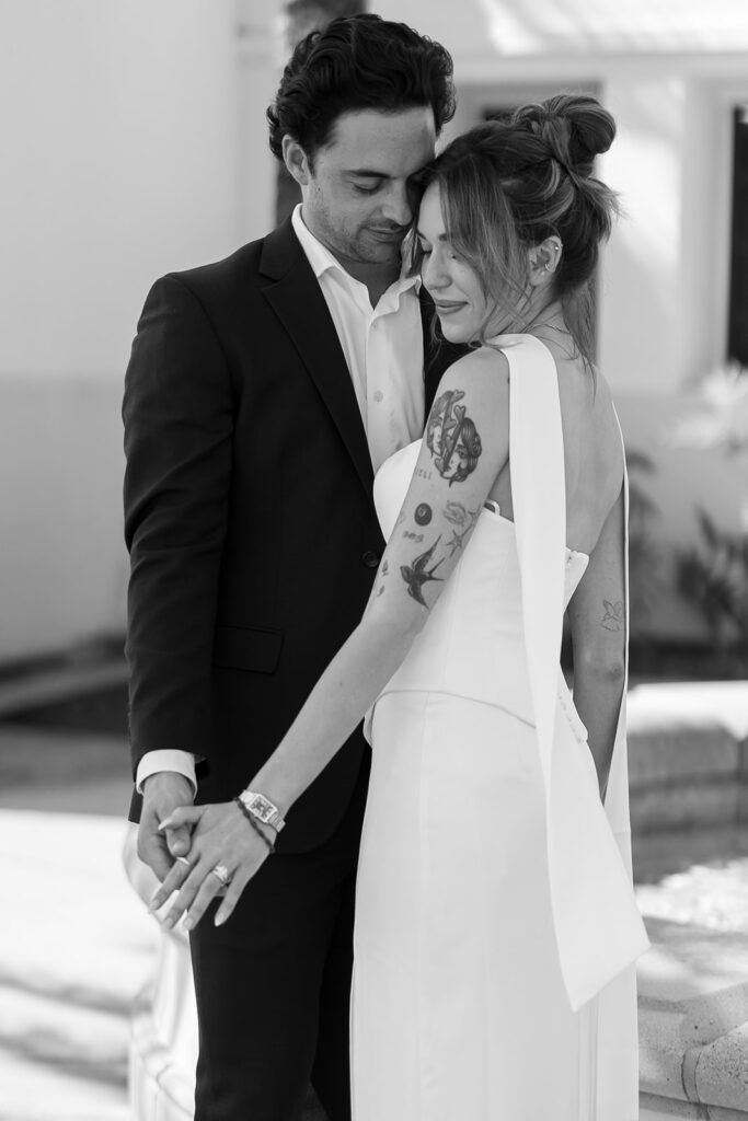Black and white portrait of a bride and groom posing together outdoors.