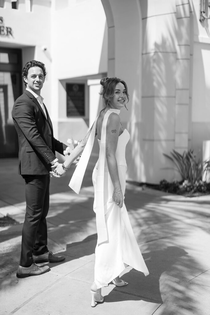 Black and white portrait of a bride and groom walking outdoors.