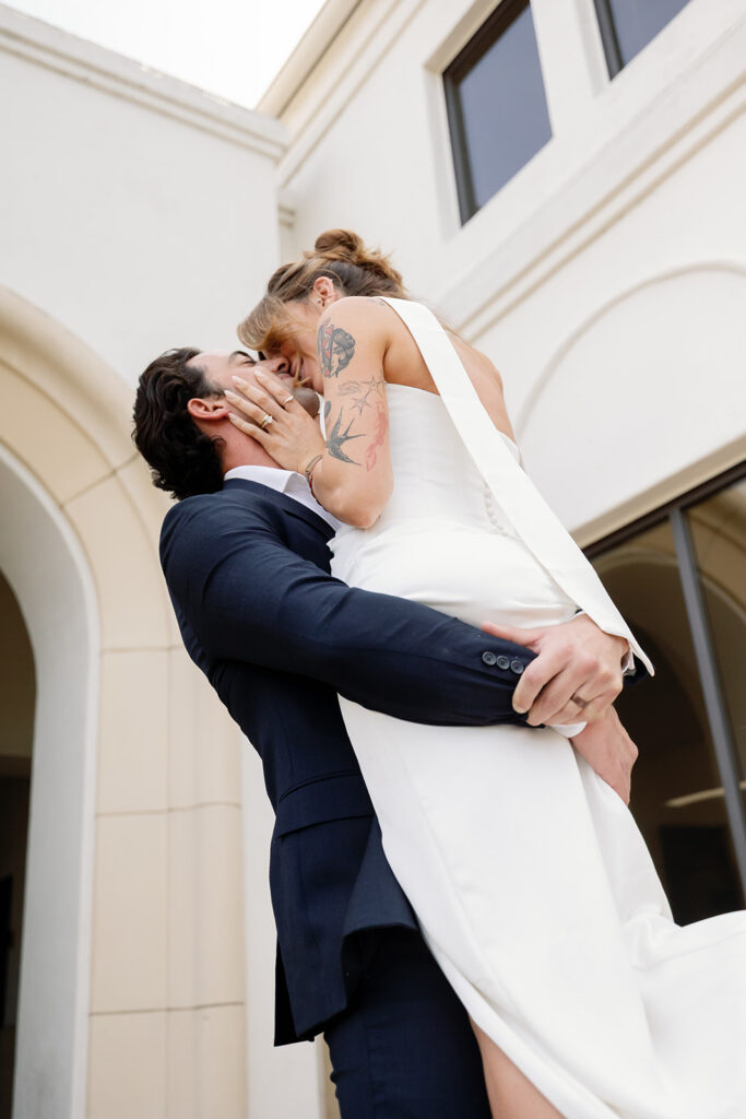 Groom lifting his bride up in the air and kissing her during their elopement portraits.