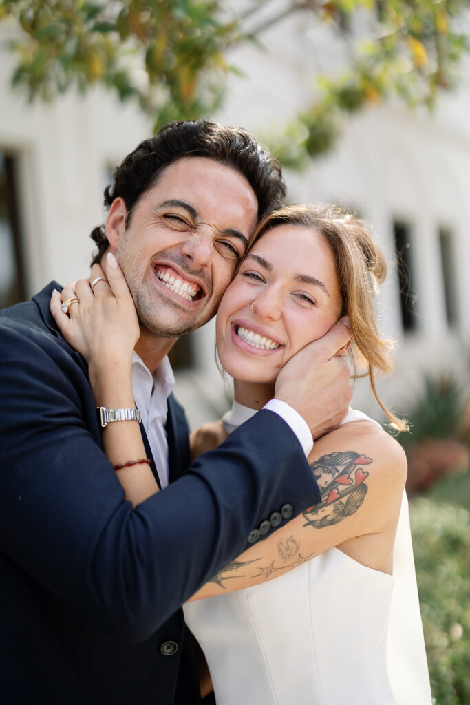 Bride and groom smiling close together outside Laguna Hills Civic Center during elopement portraits.