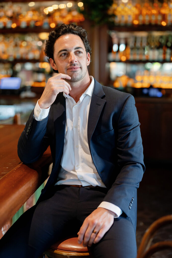 Groom portrait at bar with warm lighting and blurred background at Habana Irvine Spectrum after elopement.